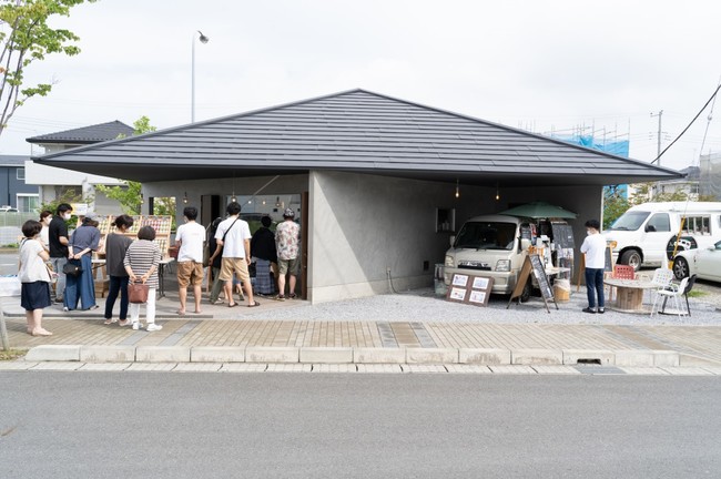 大きな屋根の軒下に多様な業態の店舗が並び、人々が集う