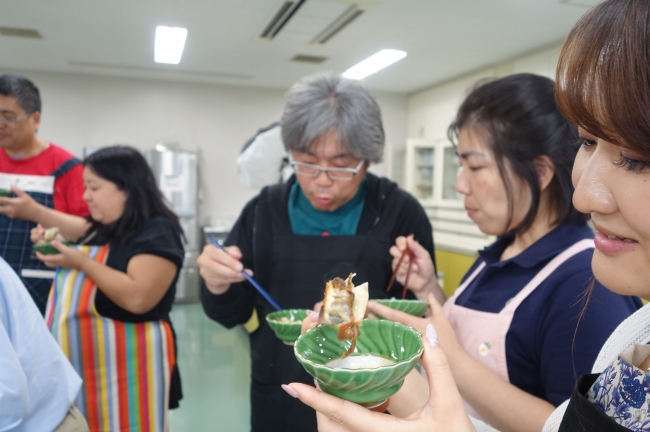 完成した赤貝餃子を食べて思わず笑顔になる様子