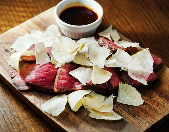 ベジマカと食べるイチボステーキ（1,200円）赤身肉のステーキにトリュフスライサーで薄くスライスしたベジマカを振りかけます。