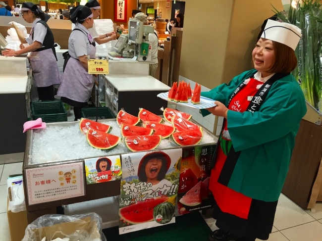 すいかの試食を勧めるスタッフ