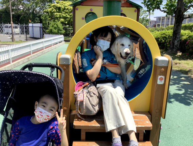 今年の初夏に撮影。前任犬のヨギが入院中のお子さんと病院前の「ぽっぽ広場」でお散歩を楽しむ様子