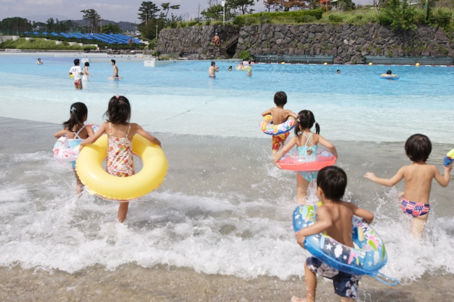 波のプールに駆け込むこどもたち