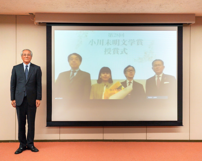 ▲上越市役所のスクリーンに東京会場を映す形での記念撮影。写真左より、上越市・村山市長、小川未明文学賞委員会・宮川会長、北川佳奈さん、菊永副会長、学研プラス・影山社長。