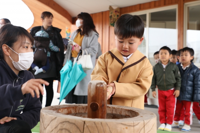 子ども用の杵と臼を使い、元気におもちをつきます。