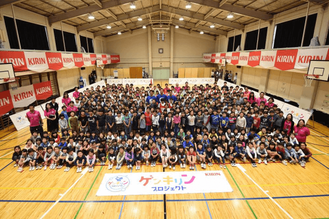 ＜中野区立桃園第二小学校1年生～6年生と選手の集合写真＞