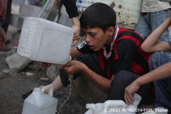 水を汲むための長い列に並びながら、水を分けてもらう少年。（シリア）© UNICEF_NYHQ2014-1125_Khabieh