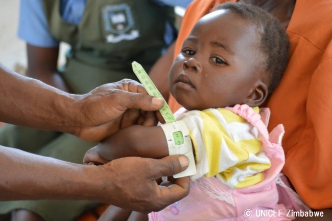 上腕部を測り、栄養状態の検査を受ける女の子。© UNICEF Zimbabwe