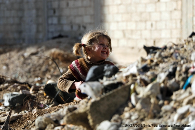 瓦礫の中笑顔を見せるシリアの女の子©UNICEF_2016_Syria_Rural Damascus_Amer Alshami 