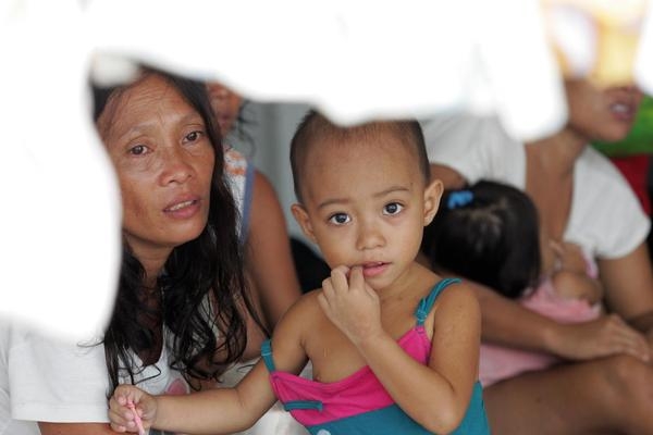 © UNICEF/NYHQ2013-0988/JEOFFREY MAITEM タクロバン市内の避難所に身を寄せている子どもと母親。市内には13の避難所におよそ1万5,000人の人々が身を寄せており、水や食糧などの支援物資を切実に求めています。