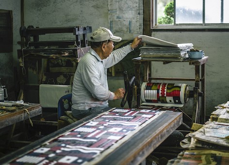 捺染された経⽷は次の織りの⼯程に向けて丁寧に巻き取ら れる。Photo Kosuke Tamura